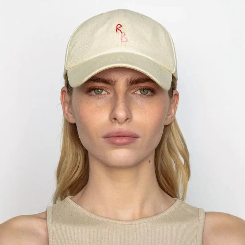 Woman wearing a beige cap with a logo on a white background
