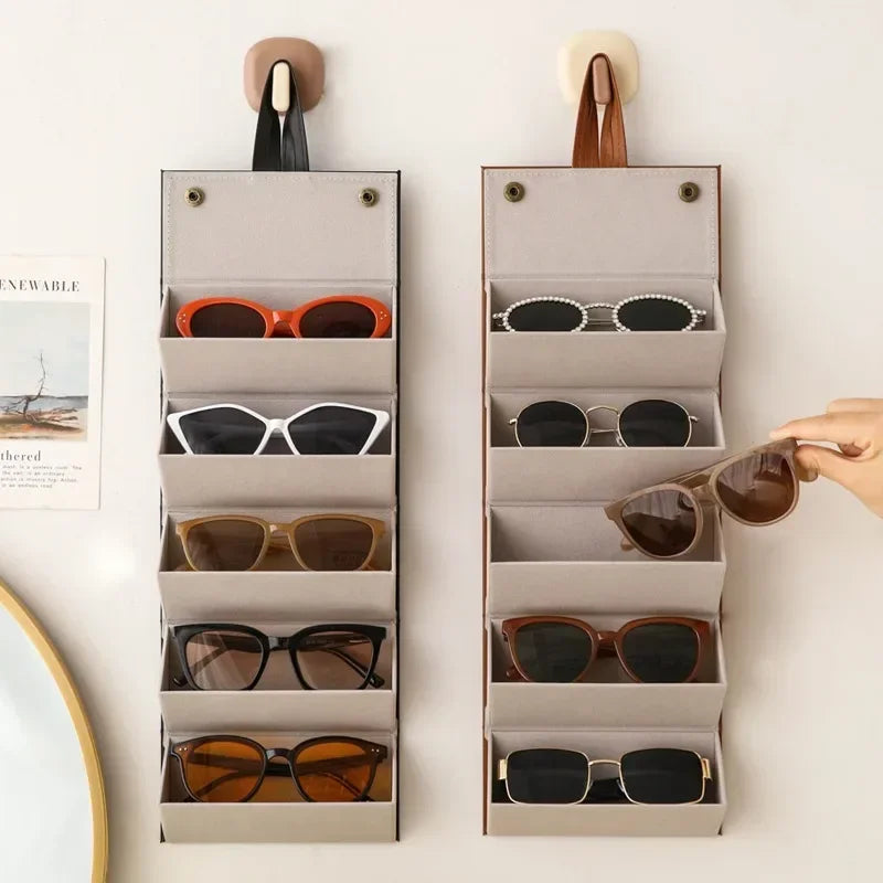 Wall-mounted sunglasses organizer with multiple compartments holding various pairs of sunglasses.